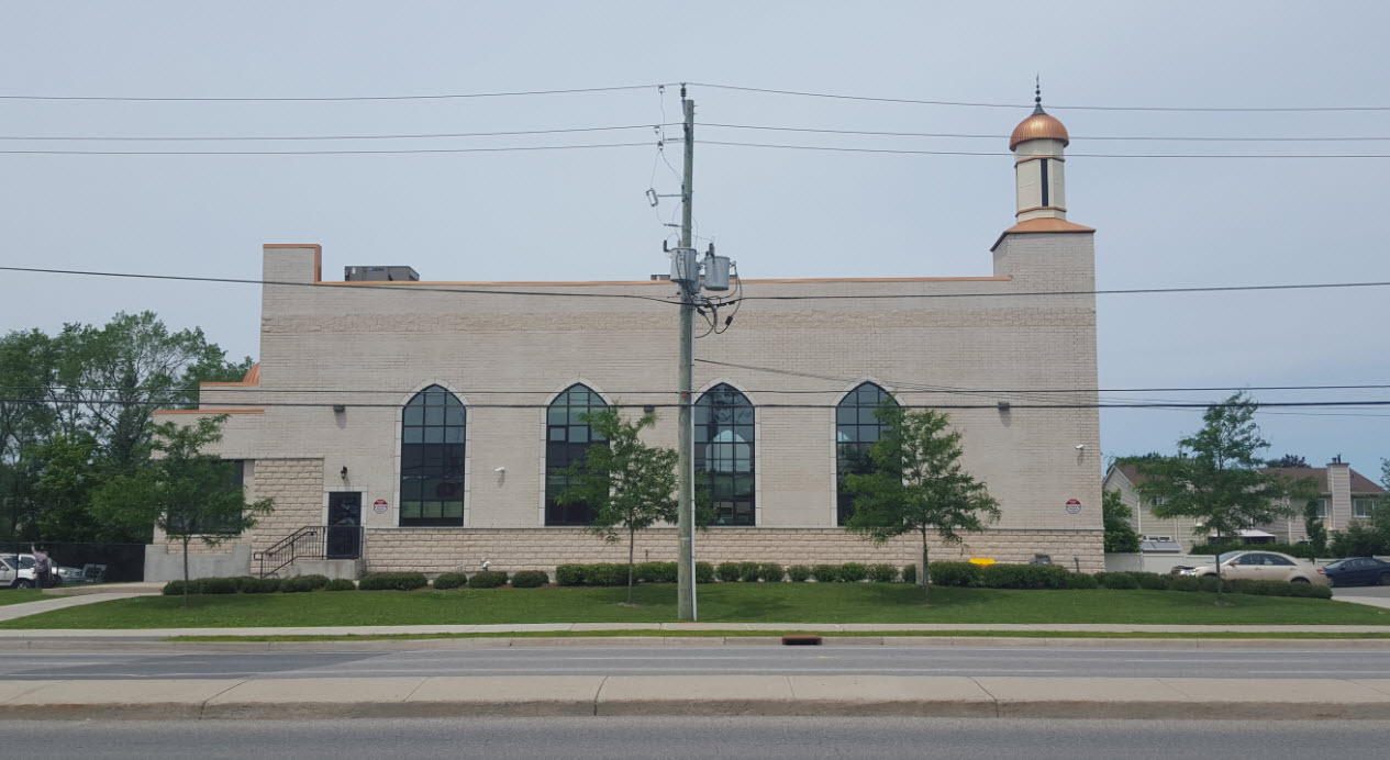 Exterior view of a modern mosque featuring expansive arched windows, reminiscent of those found in Spain.